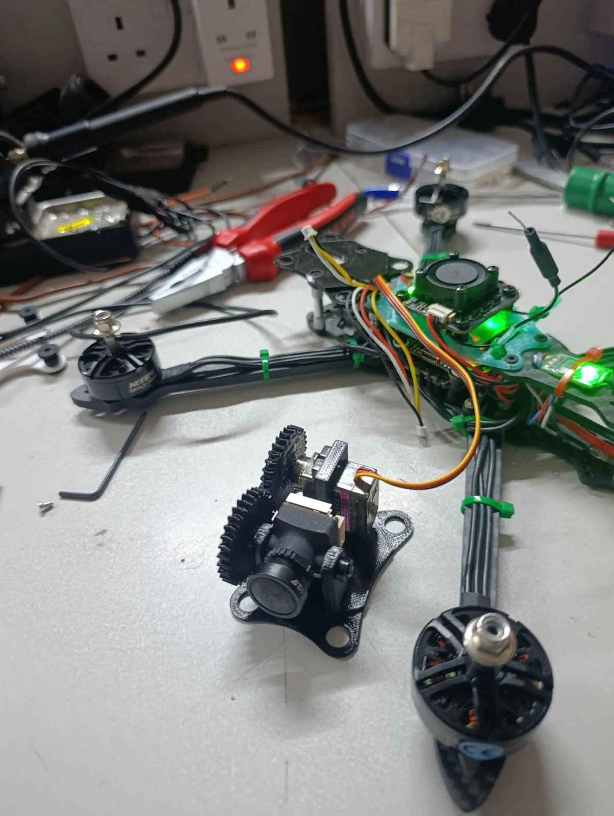 Quadcopter electronics and a 3D-printed geared mechanism on my workbench