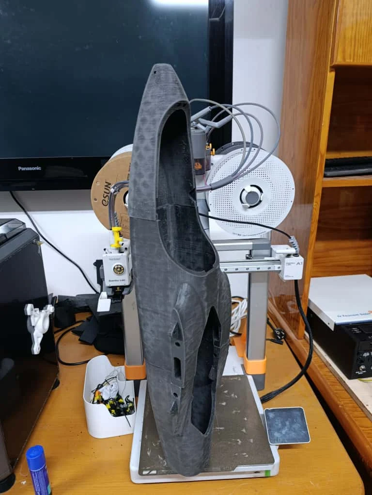 Full view of a tall 3D-printed shell beside the printer